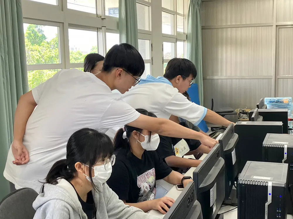 志工彎下腰,在電腦教室裡一對一指導孩子畫 3D 圖