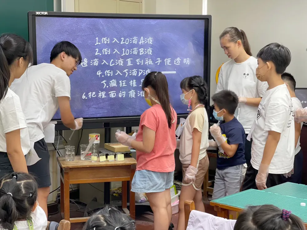 志工與孩子圍在投影幕前,照著步驟一滴一滴加入藥劑