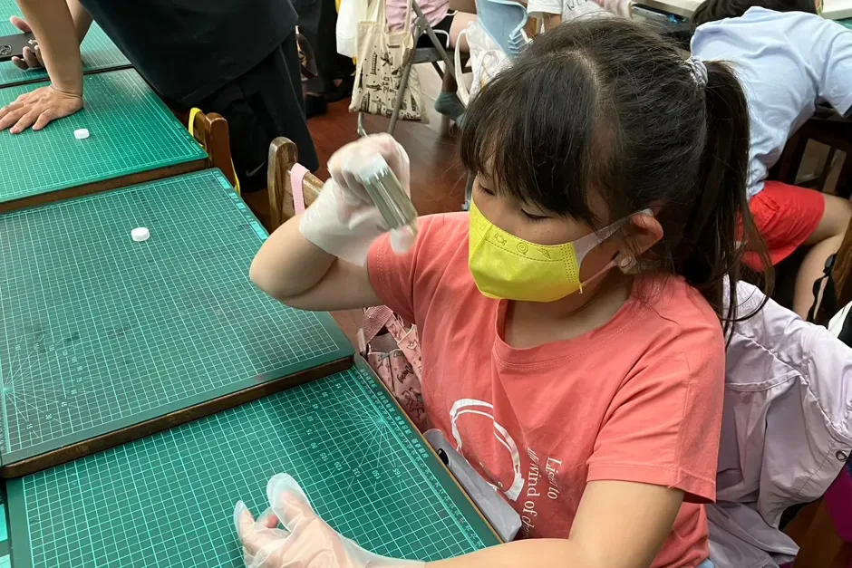 孩子戴著手套,舉起手上的玻璃瓶,觀察瓶壁形成的銀鏡