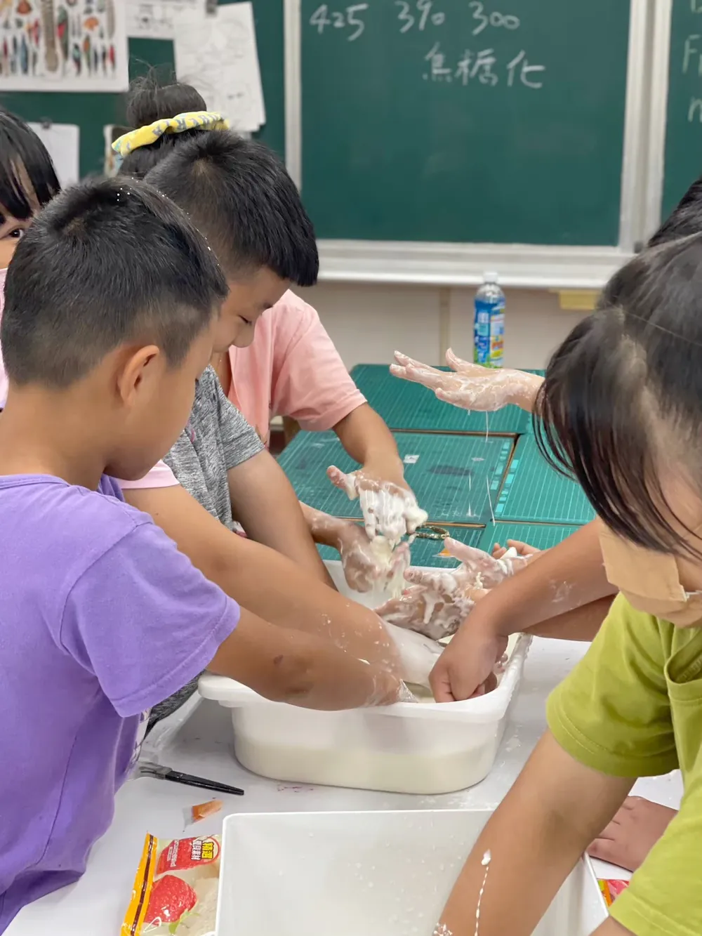 孩子們把手伸進白色盆子裡,感受又硬又軟的流體