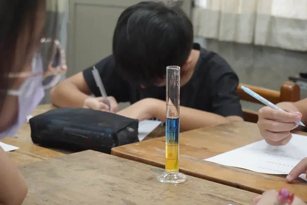 量筒裡,黃色與藍色的液體清楚分成上下兩層