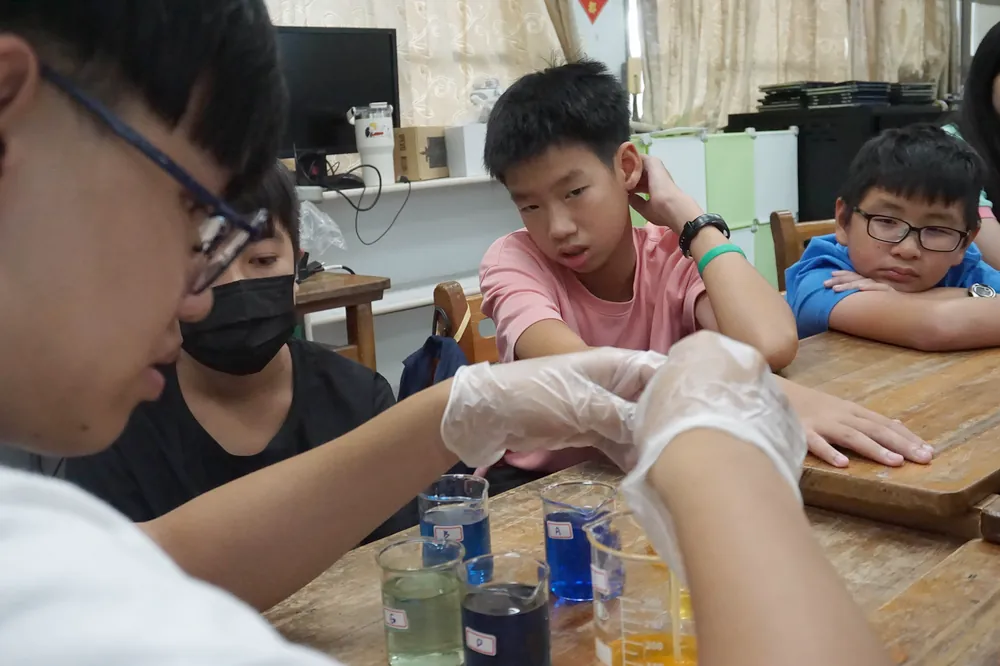 孩子們托著臉頰,看著桌上一杯杯藍色、綠色與橘色的液體