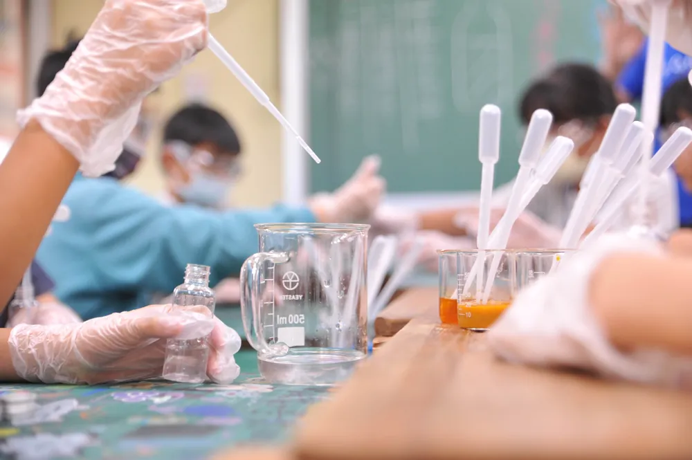 孩子與志工用滴管把液體滴進瓶中和燒杯