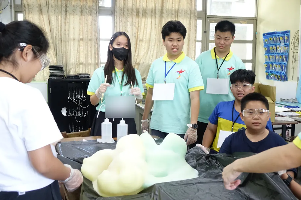 志工與孩子圍著黑色桌布,看大象牙膏的泡沫湧出